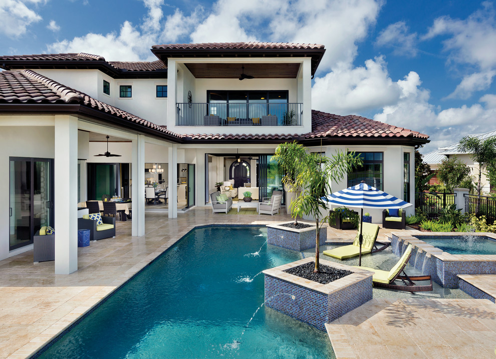 Expansive mediterranean backyard custom-shaped pool in Tampa with a water feature and tile.