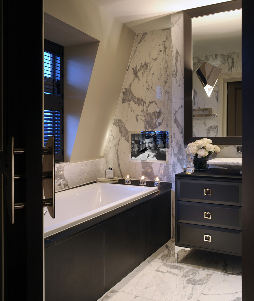 Inspiration for a contemporary bathroom in London with a vessel sink, dark wood cabinets, a drop-in tub, marble floors and flat-panel cabinets.