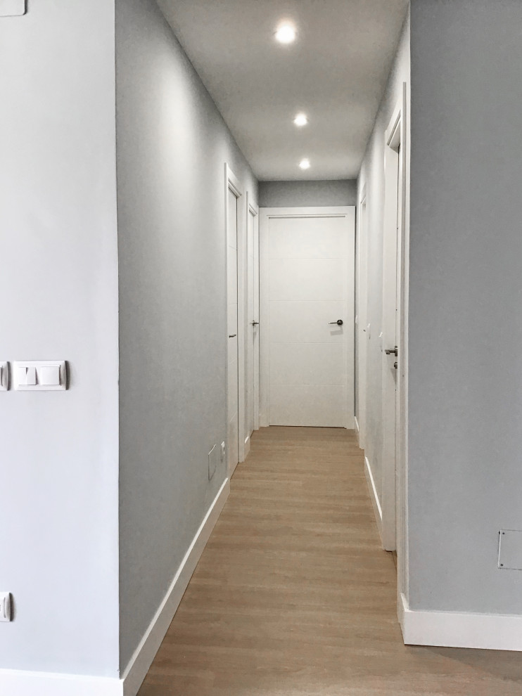 Foto på en liten funkis hall, med grå väggar, laminatgolv och brunt golv