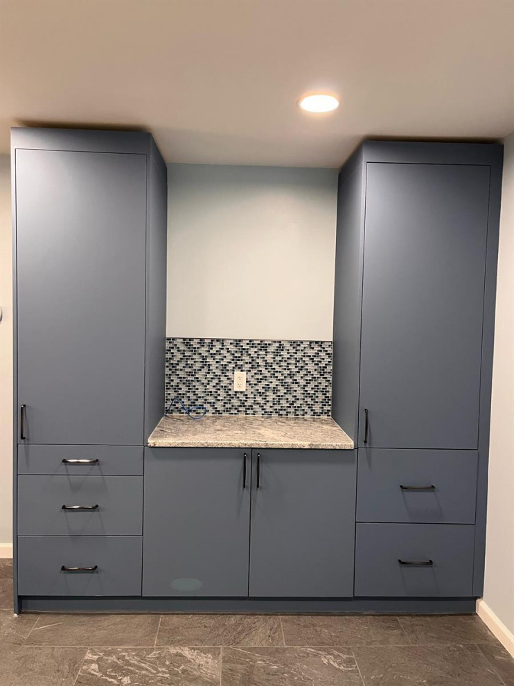 Mid-sized modern l-shaped dedicated laundry room in Bridgeport with flat-panel cabinets, blue cabinets, granite benchtops, black splashback, mosaic tile splashback, grey walls and yellow benchtop.