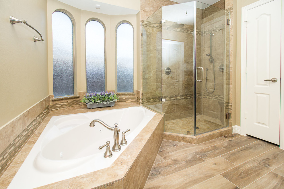 Design ideas for a mid-sized traditional master bathroom in Houston with raised-panel cabinets, dark wood cabinets, a corner tub, a corner shower, beige tile, porcelain tile, beige walls, pebble tile floors, an undermount sink, granite benchtops, beige floor, a hinged shower door and beige benchtops.
