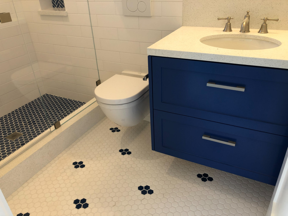 This is an example of a small beach style master bathroom in San Francisco with shaker cabinets, blue cabinets, a wall-mount toilet, white tile, ceramic tile, white walls, ceramic floors, an undermount sink, engineered quartz benchtops, blue floor, white benchtops, a niche, a single vanity and a floating vanity.