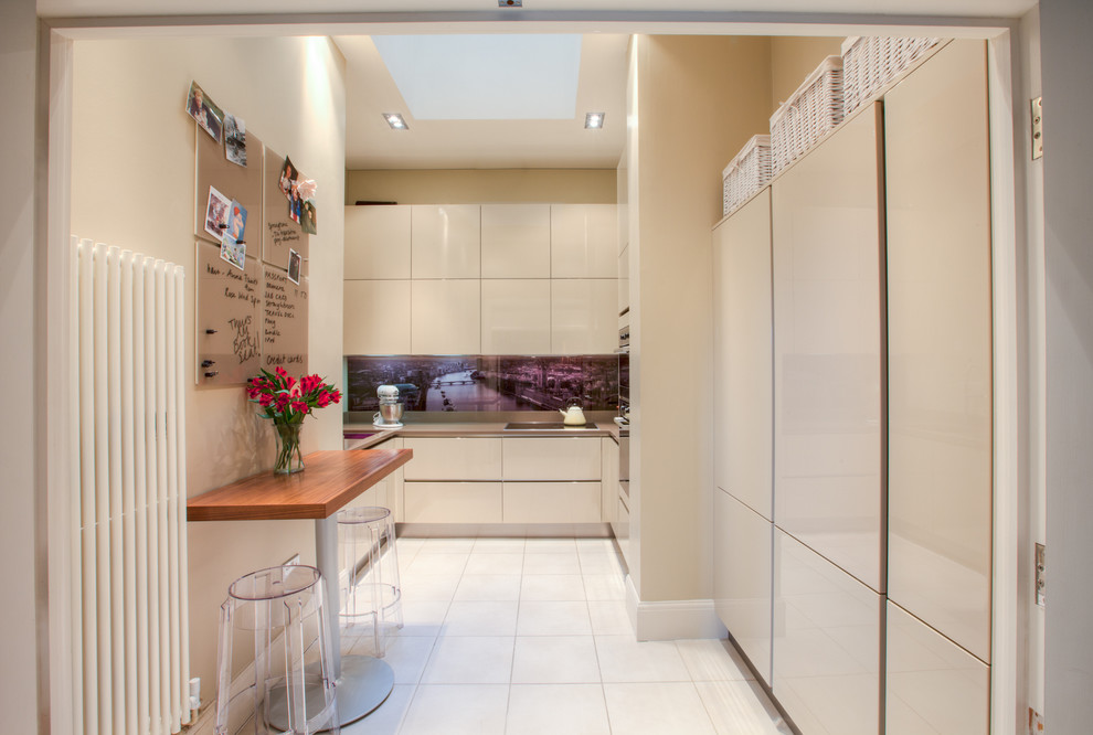 Photo of a contemporary u-shaped separate kitchen in Manchester with flat-panel cabinets, beige cabinets and glass sheet splashback.