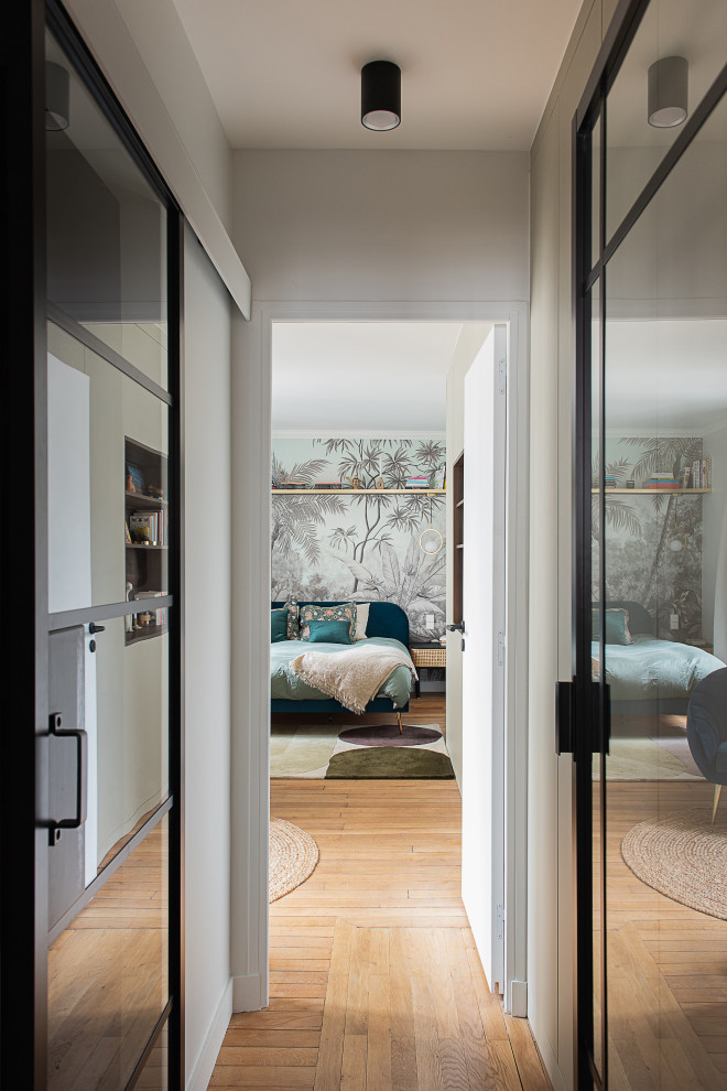 Immagine di una piccola camera matrimoniale minimalista con pareti bianche, parquet chiaro, carta da parati e abbinamento di mobili antichi e moderni