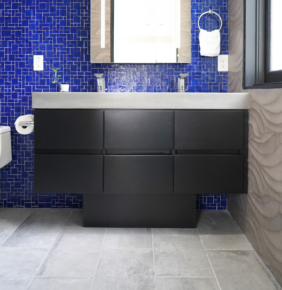 Идея дизайна: главная ванная комната среднего размера со стиральной машиной в современном стиле с плоскими фасадами, черными фасадами, душем без бортиков, биде, синей плиткой, стеклянной плиткой, серыми стенами, полом из керамогранита, раковиной с несколькими смесителями, столешницей из бетона, серым полом, открытым душем, серой столешницей, тумбой под две раковины и подвесной тумбой