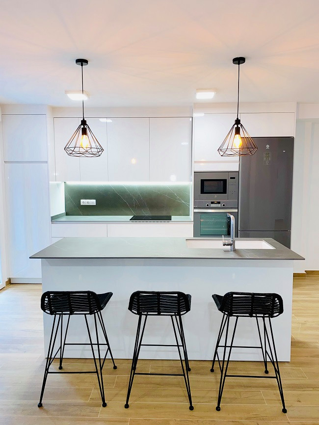 Bild på ett stort funkis grå grått kök, med en undermonterad diskho, släta luckor, vita skåp, marmorbänkskiva, grått stänkskydd, stänkskydd i porslinskakel, rostfria vitvaror, mellanmörkt trägolv, en köksö och brunt golv