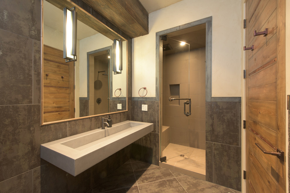 Photo of a large industrial 3/4 bathroom in Other with an alcove shower, gray tile, porcelain tile, white walls, porcelain floors, a trough sink and concrete benchtops.