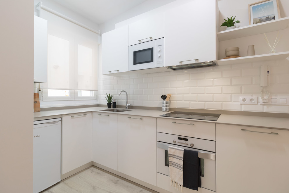 Small scandinavian l-shaped separate kitchen in Other with flat-panel cabinets, white cabinets, white splashback, subway tile splashback, no island and beige benchtop.