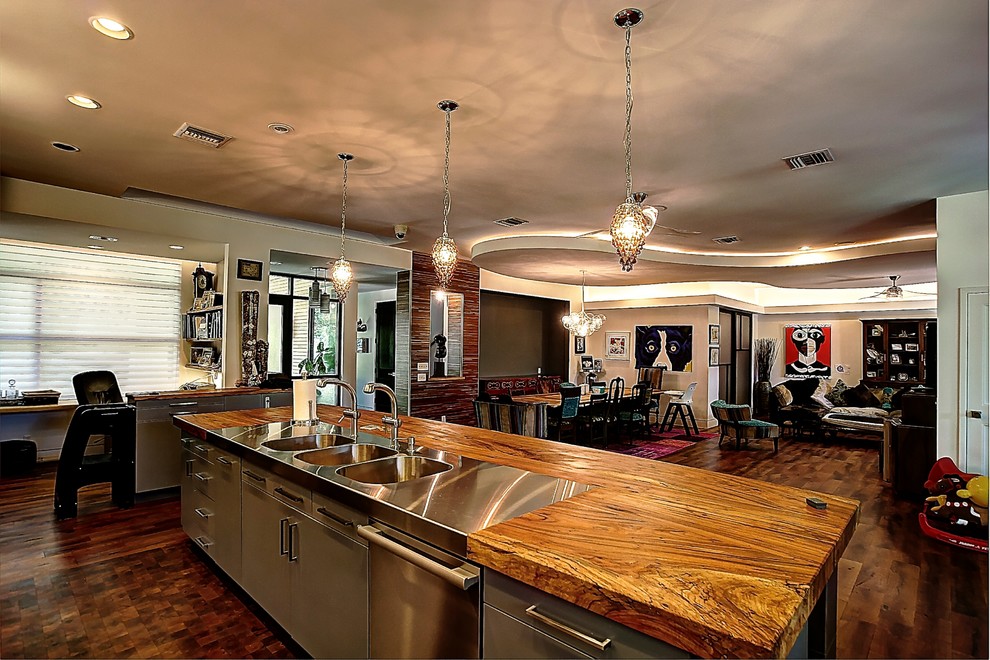This is an example of a large eclectic galley open plan kitchen in Austin with a triple-bowl sink, flat-panel cabinets, medium wood cabinets, wood benchtops, multi-coloured splashback, stainless steel appliances and medium hardwood floors.