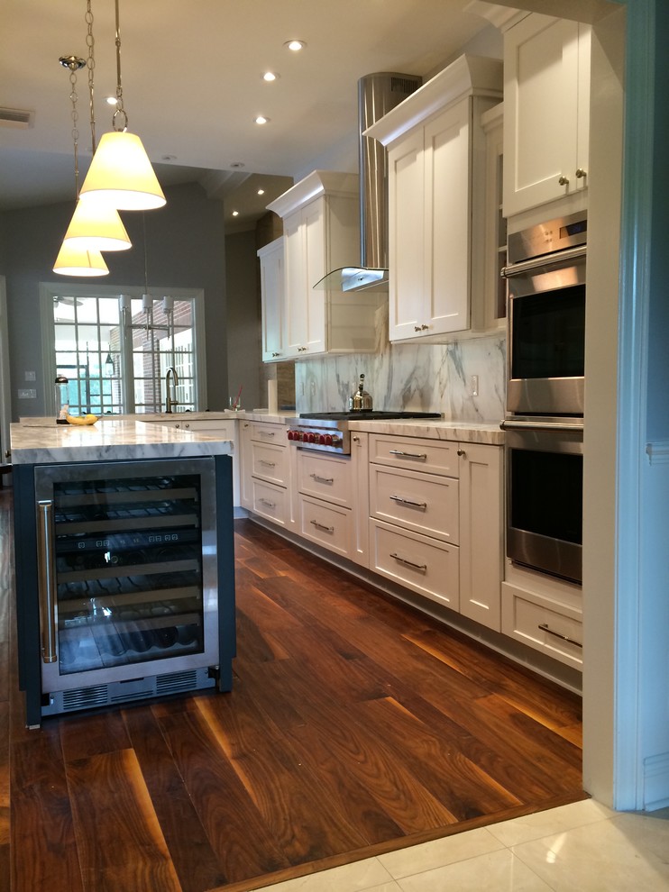 Photo of a mid-sized traditional u-shaped eat-in kitchen in Tampa with a double-bowl sink, shaker cabinets, white cabinets, marble benchtops, multi-coloured splashback, stone slab splashback, stainless steel appliances, medium hardwood floors, with island and brown floor.