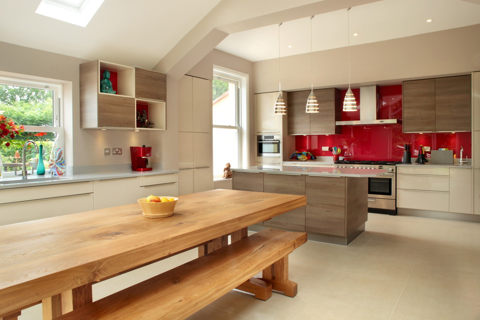 Photo of a large contemporary u-shaped open plan kitchen in Buckinghamshire with flat-panel cabinets, beige cabinets, red splashback, stainless steel appliances, with island, quartzite benchtops and glass sheet splashback.