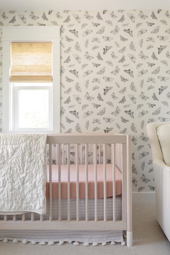 Photo of a mid-sized beach style nursery for girls in San Diego with white walls, carpet, beige floor and wallpaper.