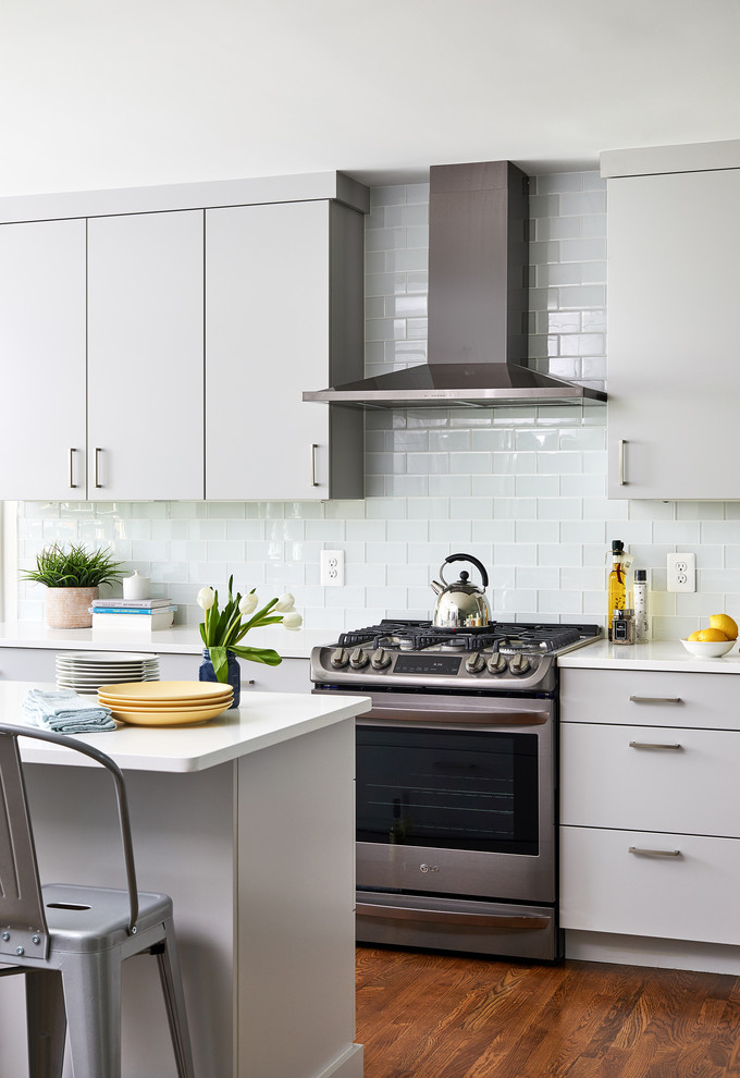 Design ideas for a mid-sized contemporary kitchen in DC Metro with subway tile splashback, medium hardwood floors, with island and white benchtop.
