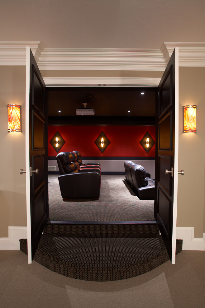 This is an example of a mid-sized traditional enclosed home theatre in Chicago with carpet, a projector screen and red walls.