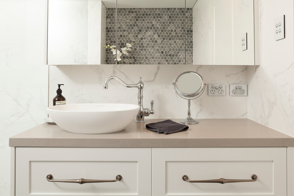 Transitional master bathroom in Auckland with shaker cabinets, white cabinets, a wall-mount toilet, multi-coloured tile, multi-coloured walls, porcelain floors, a vessel sink and engineered quartz benchtops.