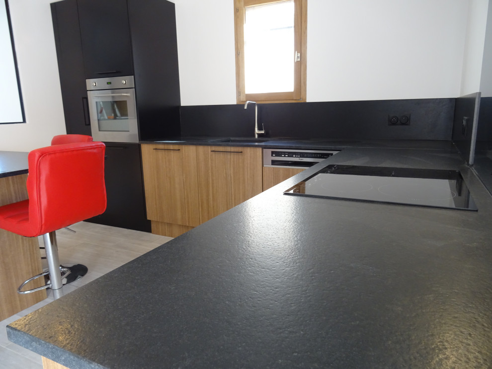 Inspiration for a mid-sized industrial l-shaped separate kitchen in Marseille with an integrated sink, beaded inset cabinets, granite benchtops, black splashback, granite splashback, stainless steel appliances, ceramic floors, a peninsula, grey floor and black benchtop.
