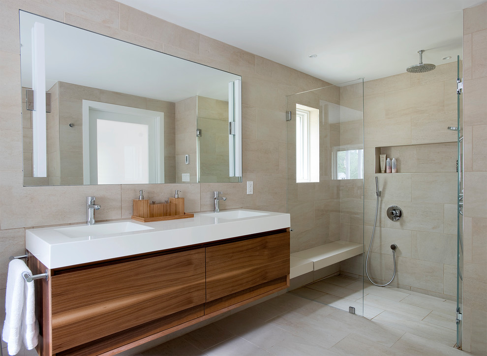 Inspiration for a mid-sized modern master bathroom in Other with flat-panel cabinets, dark wood cabinets, a freestanding tub, a curbless shower, a one-piece toilet, beige tile, porcelain tile, beige walls, porcelain floors, an integrated sink, solid surface benchtops, beige floor, a hinged shower door and white benchtops.
