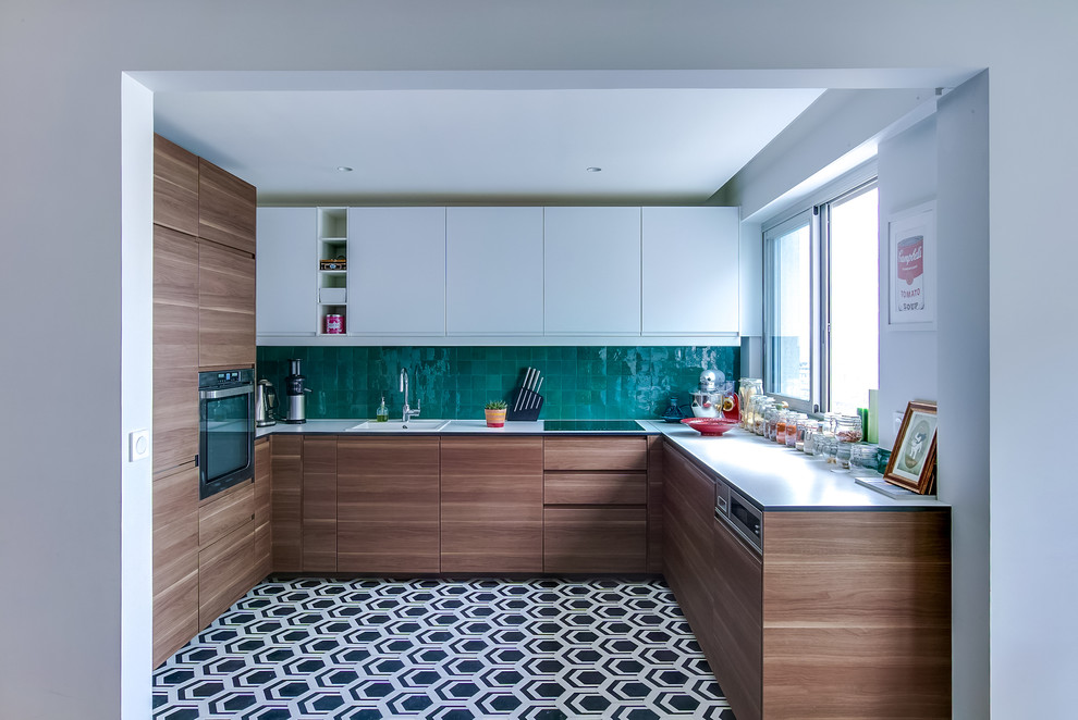 Inspiration for a mid-sized contemporary u-shaped open plan kitchen in Paris with an undermount sink, flat-panel cabinets, medium wood cabinets, laminate benchtops, green splashback, panelled appliances and cement tiles.