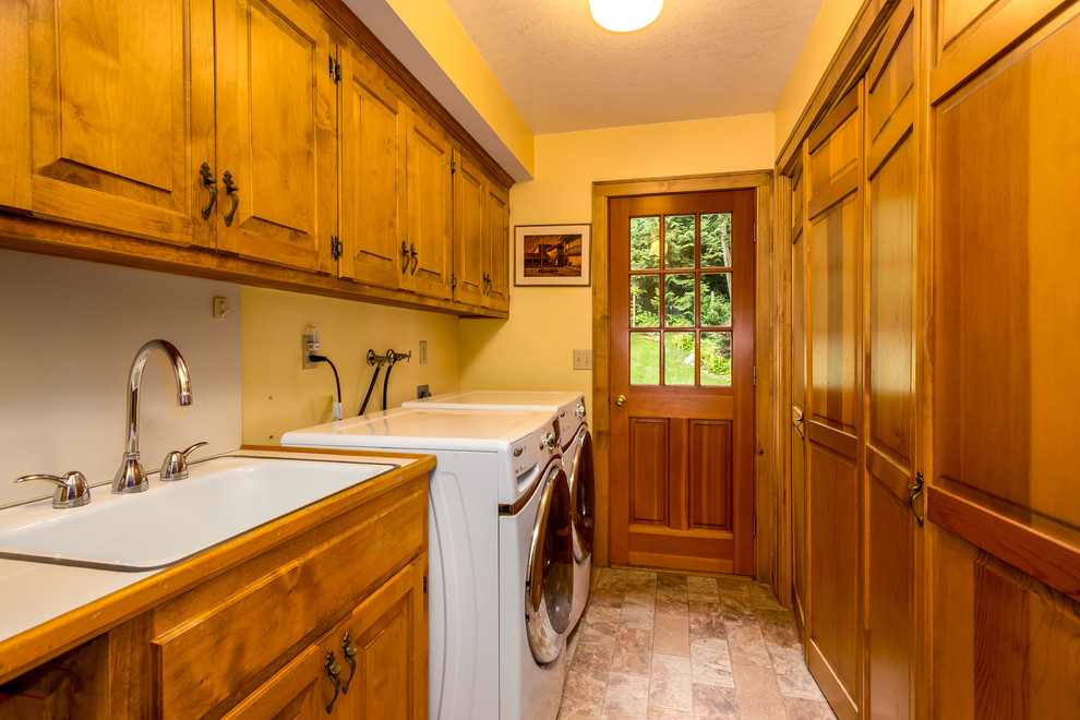 Inspiration for a large country galley utility room in Seattle with a drop-in sink, raised-panel cabinets, medium wood cabinets, laminate benchtops, yellow walls and a side-by-side washer and dryer.