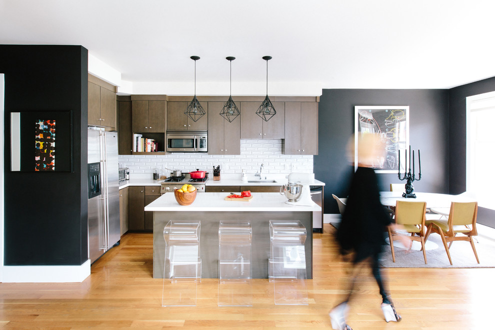 Contemporary l-shaped open plan kitchen in San Francisco with an undermount sink, flat-panel cabinets, dark wood cabinets, quartz benchtops, white splashback, ceramic splashback, stainless steel appliances, light hardwood floors and with island.
