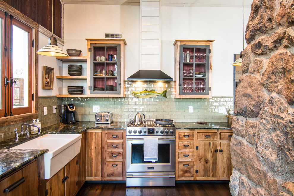 Country l-shaped kitchen in Baltimore with a farmhouse sink, glass-front cabinets, medium wood cabinets, green splashback, subway tile splashback, stainless steel appliances, dark hardwood floors, no island, brown floor and multi-coloured benchtop.