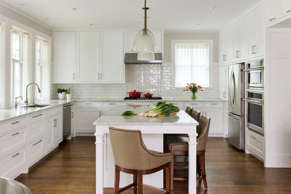 Enclosed kitchen - mid-sized transitional galley medium tone wood floor and brown floor enclosed kitchen idea in Minneapolis with an undermount sink, shaker cabinets, white cabinets, granite countertops, white backsplash, subway tile backsplash, stainless steel appliances, an island and white countertops