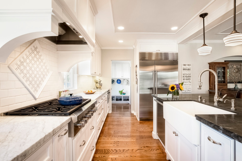 Large traditional single-wall eat-in kitchen in San Francisco with a farmhouse sink, beaded inset cabinets, white cabinets, granite benchtops, white splashback, porcelain splashback, stainless steel appliances, medium hardwood floors and with island.