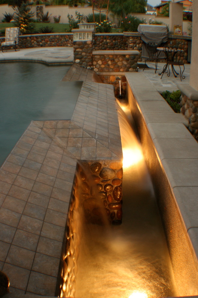 Photo of a mid-sized traditional backyard custom-shaped natural pool in Los Angeles with a water feature.