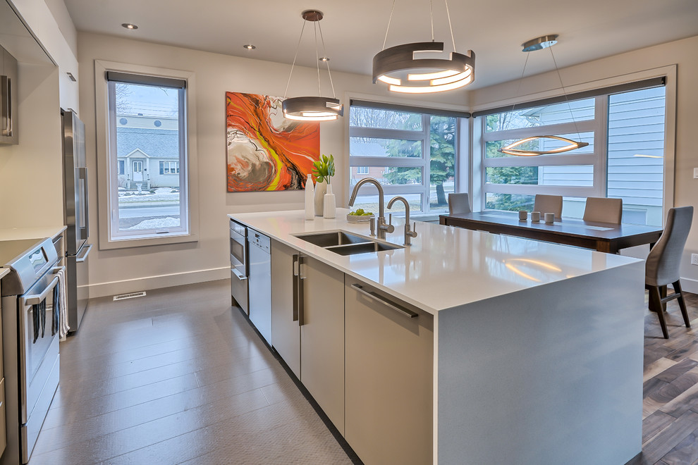 This is an example of a mid-sized modern eat-in kitchen in Montreal with an undermount sink, flat-panel cabinets, grey cabinets, quartz benchtops, grey splashback, ceramic splashback, stainless steel appliances, cork floors, with island and grey floor.