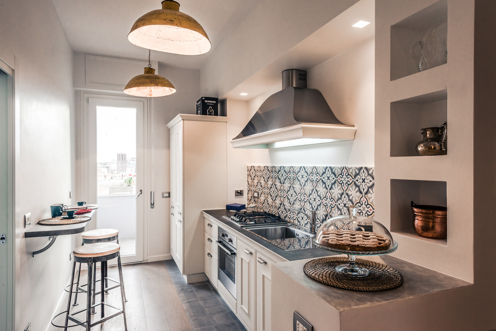 Photo of a transitional single-wall separate kitchen in Rome with a drop-in sink, raised-panel cabinets, white cabinets and stainless steel appliances.