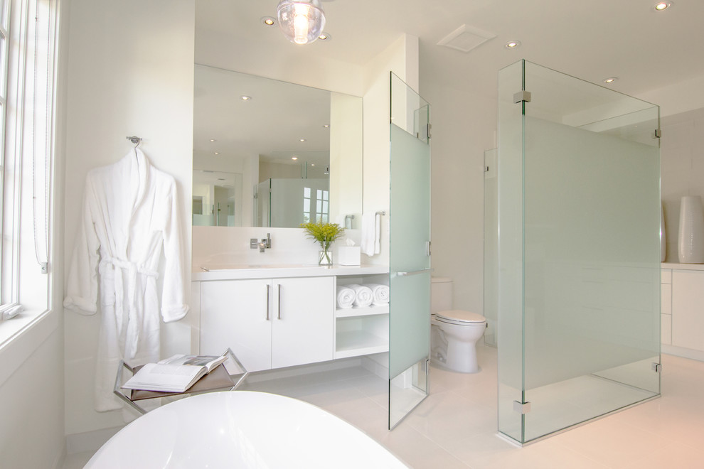 This is an example of a contemporary master bathroom in DC Metro with flat-panel cabinets, white cabinets, a freestanding tub, a two-piece toilet, white walls and an enclosed toilet.
