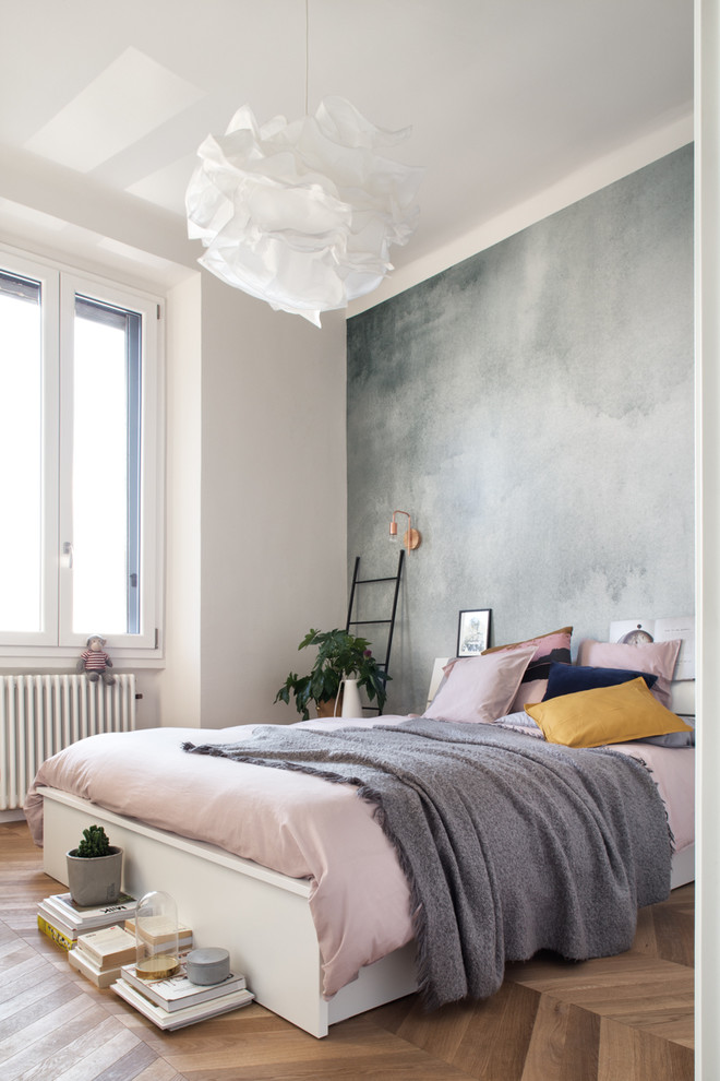 Photo of a scandinavian bedroom in Milan with white walls, medium hardwood floors and brown floor.