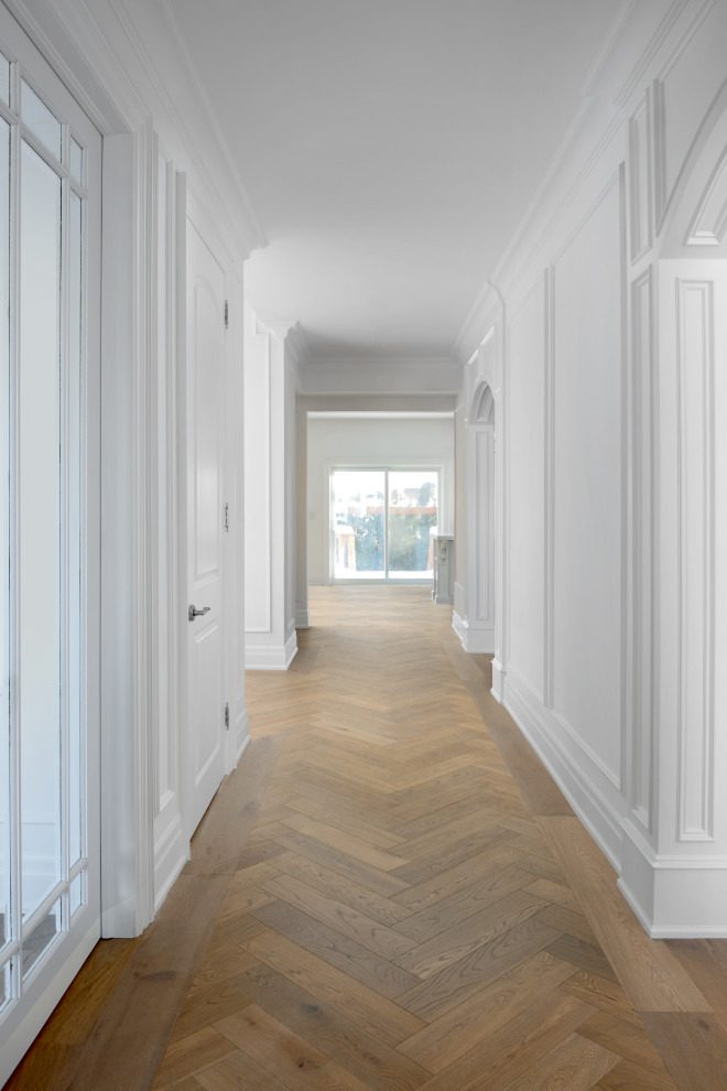 Ejemplo de recibidores y pasillos tradicionales renovados grandes con paredes blancas, suelo de madera en tonos medios y panelado