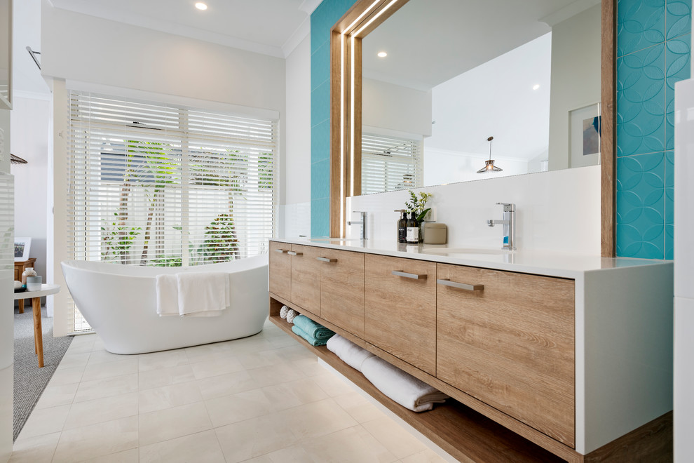 Design ideas for a beach style master bathroom in Perth with flat-panel cabinets, light wood cabinets, a freestanding tub, blue tile, blue walls, a wall-mount sink, white floor and white benchtops.