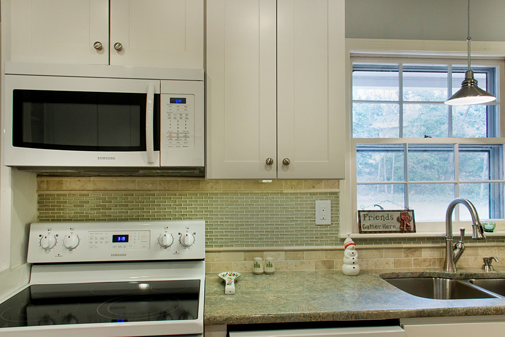 Example of a transitional l-shaped eat-in kitchen design with an undermount sink, shaker cabinets, white cabinets, granite countertops, green backsplash, glass tile backsplash and white appliances