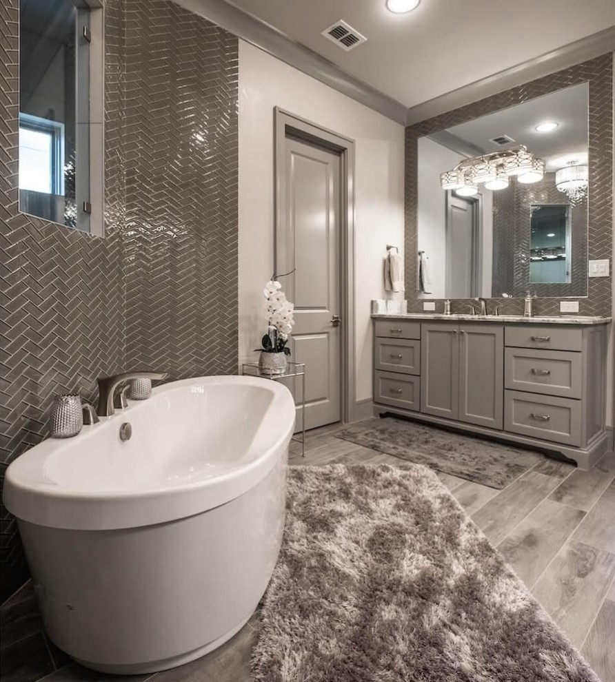 Inspiration for a transitional master bathroom in Dallas with recessed-panel cabinets, grey cabinets, a freestanding tub, an open shower, gray tile, glass tile, grey walls, porcelain floors, marble benchtops, grey floor, an open shower and white benchtops.