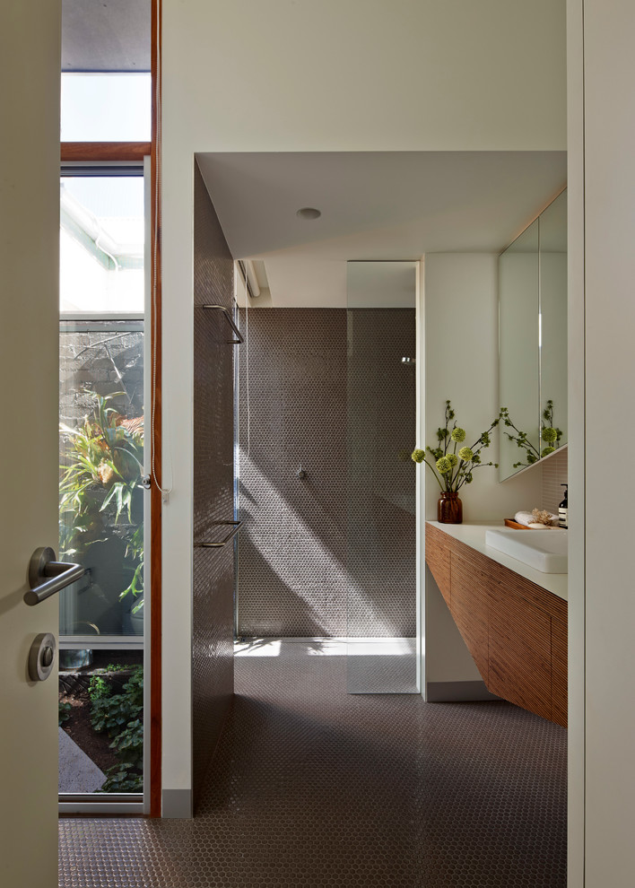 Inspiration for a mid-sized contemporary master bathroom in Melbourne with a drop-in sink, flat-panel cabinets, light wood cabinets, wood benchtops, an open shower, gray tile, ceramic tile, white walls and mosaic tile floors.
