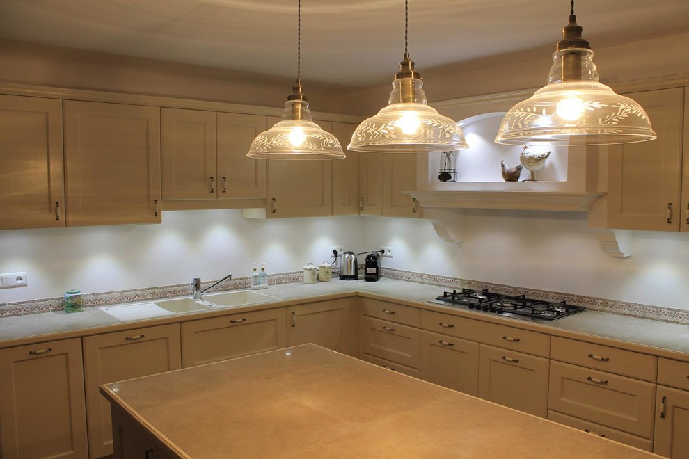 This is an example of a large traditional l-shaped open plan kitchen in Nice with a double-bowl sink, recessed-panel cabinets, beige cabinets, tile benchtops, multi-coloured splashback, travertine splashback, stainless steel appliances, terra-cotta floors, with island and multi-coloured floor.