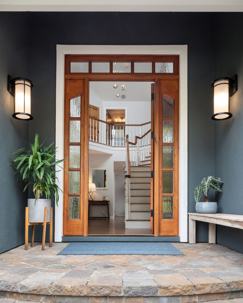 Large transitional medium tone wood floor and brown floor front door photo with blue walls and a medium wood front door
