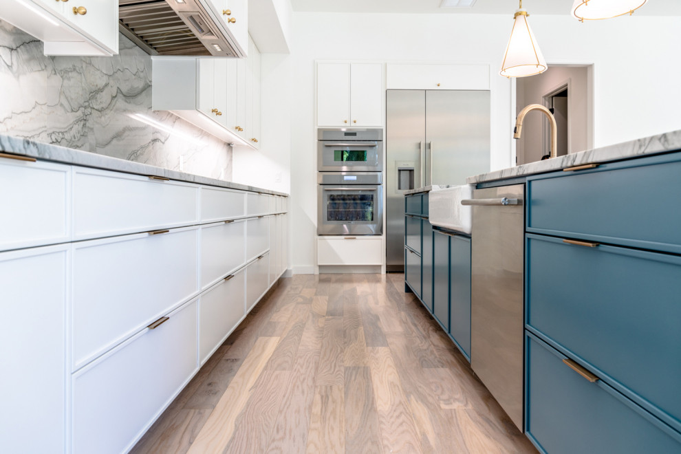Photo of a medium sized contemporary l-shaped kitchen/diner in Austin with a submerged sink, flat-panel cabinets, white cabinets, granite worktops, stainless steel appliances, medium hardwood flooring, an island and multicoloured worktops.