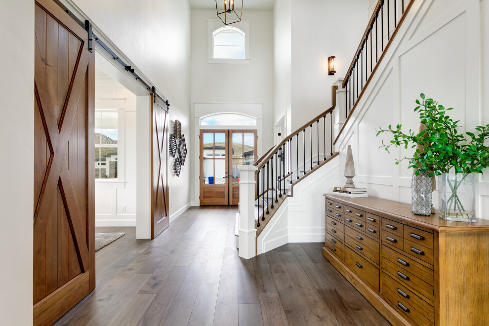 Photo of a large transitional entry hall in Boise with white walls, medium hardwood floors, a double front door, a medium wood front door, brown floor and decorative wall panelling.
