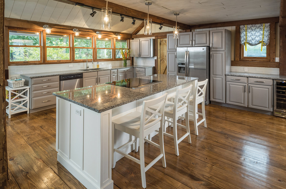 This is an example of a large country kitchen in Louisville with raised-panel cabinets, grey cabinets, granite benchtops, stainless steel appliances, medium hardwood floors, with island, brown floor, a double-bowl sink and window splashback.