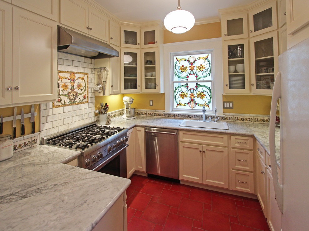 Photo of a traditional u-shaped kitchen in San Francisco with glass-front cabinets, stainless steel appliances, a drop-in sink and beige cabinets.