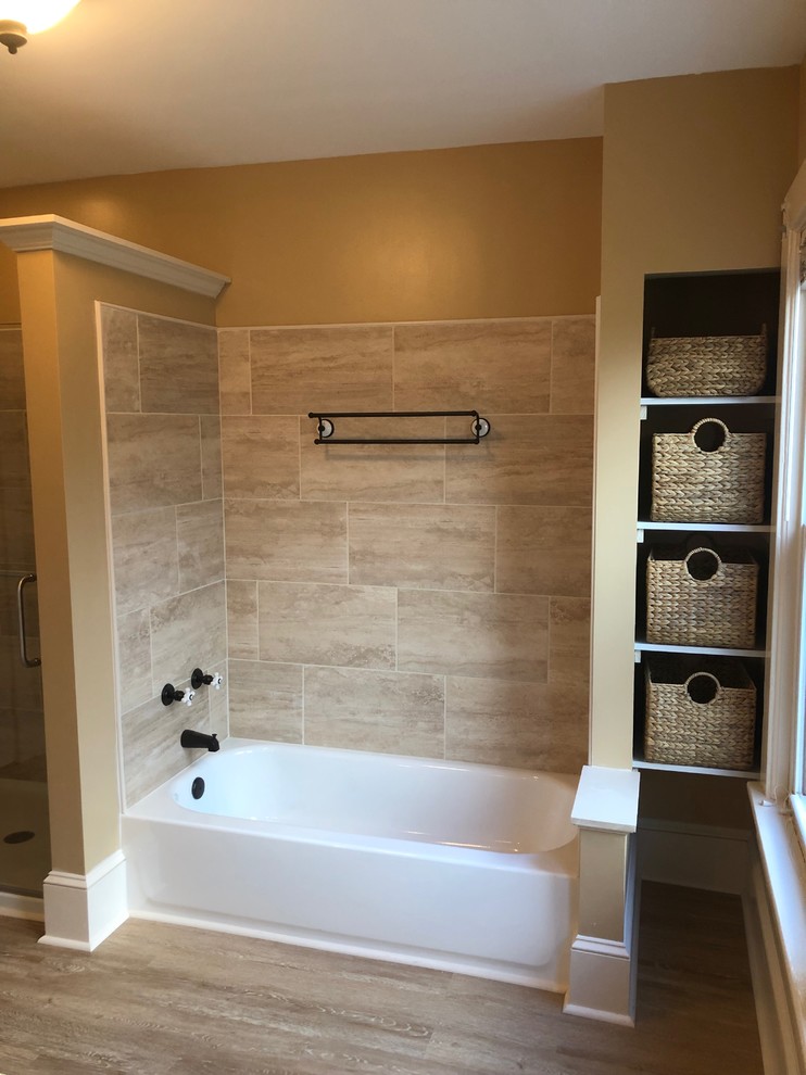Design ideas for a mid-sized modern master bathroom in New York with furniture-like cabinets, beige cabinets, an alcove tub, an alcove shower, a two-piece toilet, beige tile, cement tile, brown walls, vinyl floors, an undermount sink, engineered quartz benchtops, brown floor, a hinged shower door and beige benchtops.