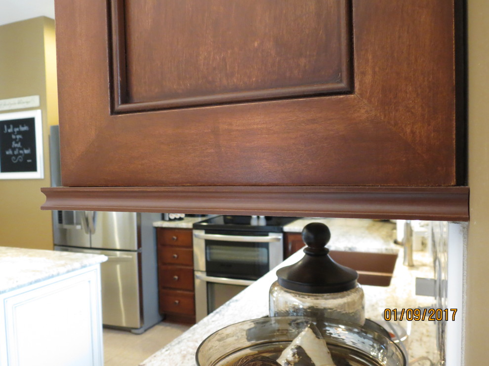 Example of a mid-sized transitional l-shaped ceramic tile eat-in kitchen design with an undermount sink, raised-panel cabinets, distressed cabinets, granite countertops, white backsplash, porcelain backsplash, stainless steel appliances and an island