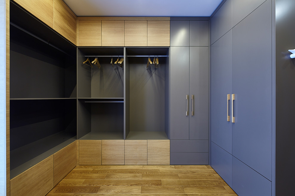 Large contemporary gender-neutral walk-in wardrobe in Moscow with medium wood cabinets, laminate floors, beige floor and flat-panel cabinets.