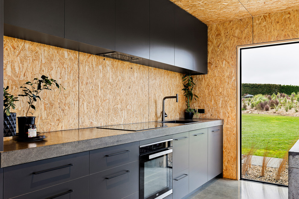 ラグジュアリーな中くらいなインダストリアルスタイルのおしゃれなキッチン (黒いキャビネット、コンクリートカウンター、木材のキッチンパネル、グレーのキッチンカウンター) の写真