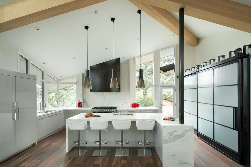 Design ideas for a contemporary l-shaped kitchen in Denver with an undermount sink, flat-panel cabinets, grey cabinets, solid surface benchtops, white splashback, stone slab splashback, panelled appliances, dark hardwood floors, with island, brown floor and white benchtop.