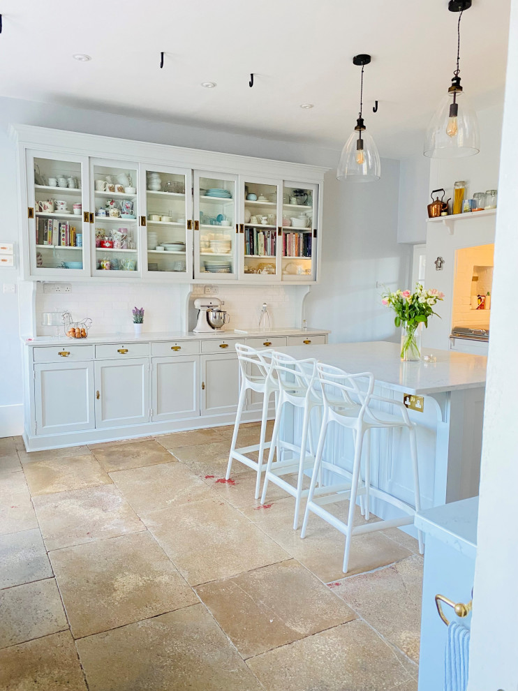 Inspiration for a large traditional enclosed kitchen in Wiltshire with a belfast sink, shaker cabinets, grey cabinets, quartz worktops, white splashback, porcelain splashback, coloured appliances, marble flooring, an island, beige floors, white worktops and a chimney breast.