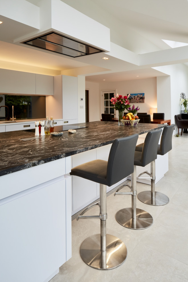 Mid-sized contemporary single-wall eat-in kitchen in Other with flat-panel cabinets, white cabinets, granite benchtops, metallic splashback, mirror splashback, panelled appliances, with island and blue benchtop.